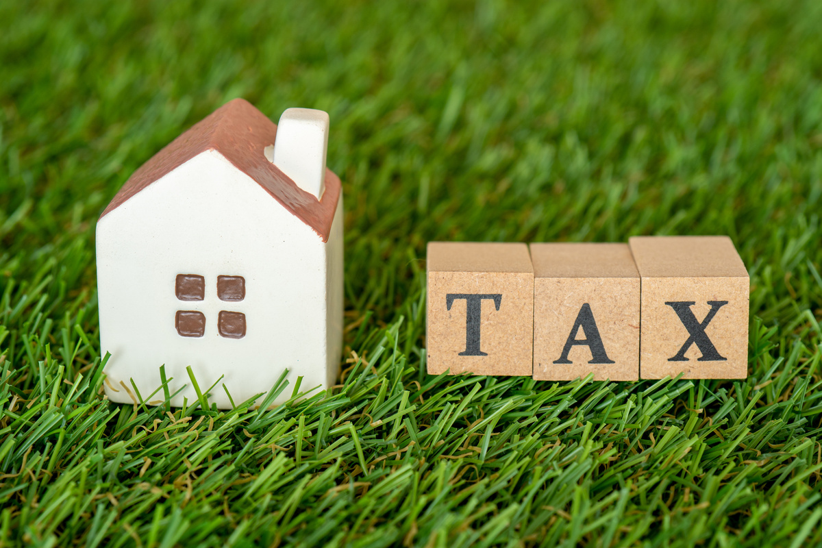 Concept of housing tax (miniature house and the word TAX)